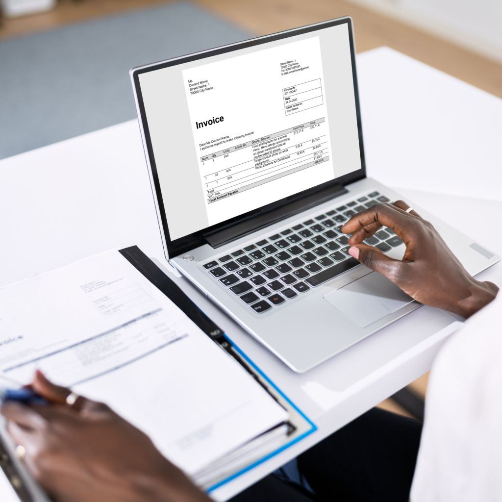 homem mexendo no notebook com um caderno ao lado fazendo anotações